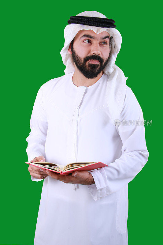 一名年轻的阿拉伯学生穿着阿联酋传统服装，面带微笑拿着一本书的肖像(UAE book EMIRATI)